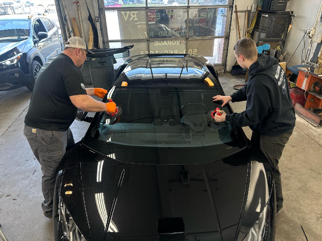 Technicians installing a windshield on a sports car